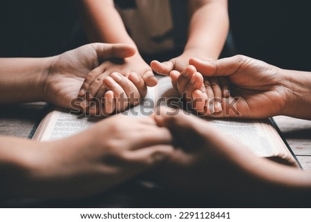Christian family praying together concept. Child and mother worship God in home. Woman and boy hands praying to god with the bible begging for forgiveness and believe in goodness.