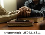 Christian group of people holding hands praying together over holy bible, comforting and praying together.