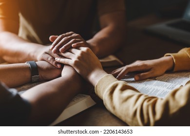 Christian group of people holding hands praying worship together to believe and Bible on a wooden table for devotional for prayer meeting concept. - Shutterstock ID 2206143653