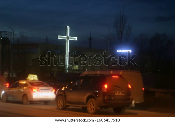Christian, a\
large cross with white LED backlight on a highway with vehicles\
under a blue, summer sky.  Night\
background