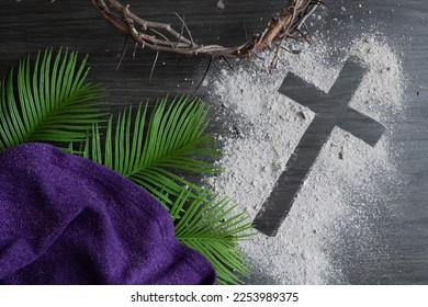 Christian lent background with cross of ashes, palm leaves, crown of thorns and purple cloth