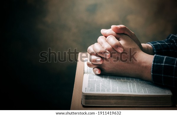Christian life crisis prayer to god. Man Pray for\
god blessing to wishing have a better life. man hands praying to\
god with the bible. believe in goodness. Holding hands in prayer on\
a wooden table.