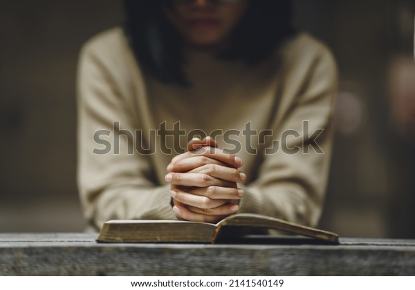 Christian life crisis prayer to god. Woman\
holding hands pray for god blessing to wishing have a better life\
on a wooden table. Woman hands praying to god with the bible.\
believe in goodness.
