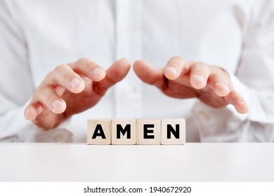 Christian man holds his hands over the wooden cubes with the word amen.