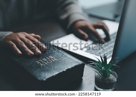 Christian online technology concept. Hands praying of christian with digital computer laptop, Online live church for sunday service. Asian catholic woman are reading Holy bible book and online study.