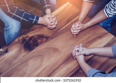 Christian people prays together around wooden table. prayer meeting small group concept.