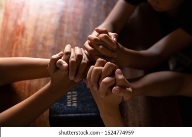 Christian People Prays Together Around Wooden Table With Bible.