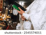 Christian priest with bible in hands, in cassock conducts church service, prays in church. Close-up photo, religion concept.