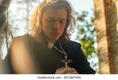 Christian priest with cross praying by the church.