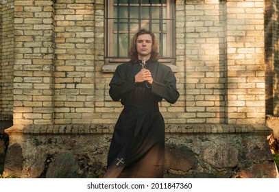 Christian priest with cross standing by the church.
