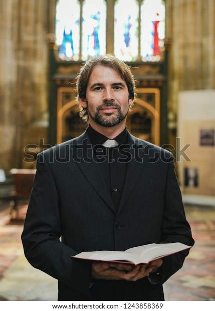 Christian priest standing by\
the altar