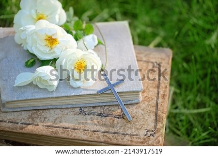 Christian religion background. old biblical books, Christian cross and rose flowers in garden. symbol of Pentecost, Easter, Orthodox palm Sunday. Lent, Faith in God, Church holidays concept