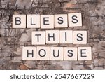 Christian religious background concept. Bless This House written with wooden block letters on natural wood bark background.