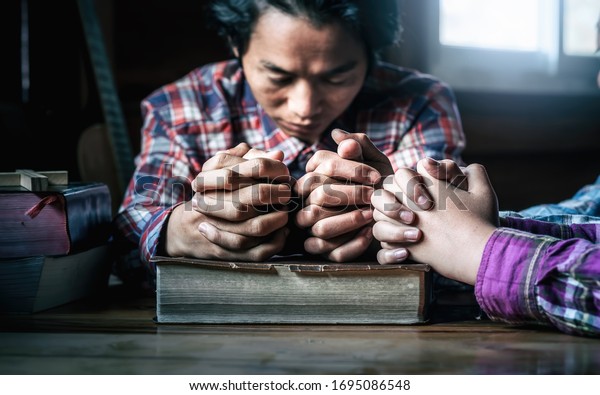 Christian small group\
praying together around wooden table with bible in home room,\
Christian meeting\
concept