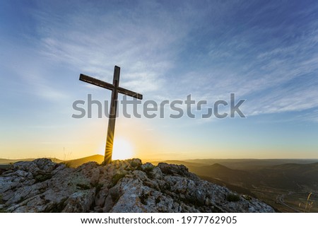 Christian symbol, Wooden Catholic cross on the top of a mountain at sunrise. 