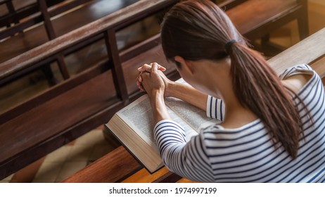 Christian Woman Praying On Holy Bible In The Public Church. Woman Pray For God Blessing To Wishing Have A Better Life And Believe In Goodness.