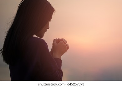 Christian woman praying worship at sunset. Hands folded in prayer. worship god with christian concept religion.