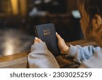 Christian woman reading bible in an ancient Catholic temple. Reading the Holy Bible in temple. Concept for faith, spirituality and religion. Peace, hope, dreams concept