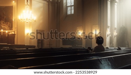 Christian Woman Sits Piously in Church, Praying, Seeks Guidance and Solace from Religious Faith and Spiritual Belief in God. Cinematic Camera Moving from Ceiling Painting of Jesus Christ to a Woman