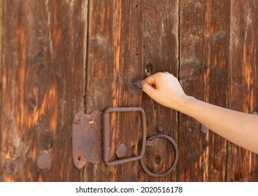 Christian woman's hand knocking on an old wooden door. Seek and find God and Jesus Christ. Faith, hope, love, obedience, forgiveness, mercy, grace biblical concept. Revelation message of the gospel.