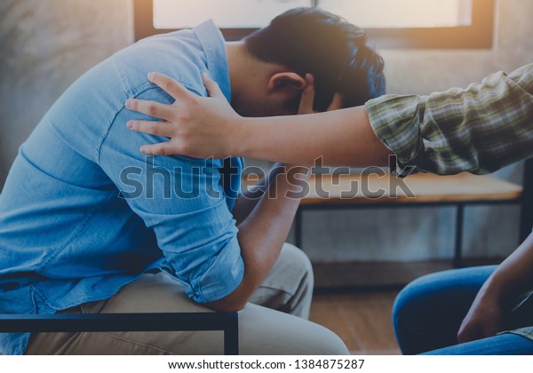 A Christian young man 
praying for his friends while sitting on wooden chair at church
prayer room to encourage and support him in his problem and
spiritual growth.