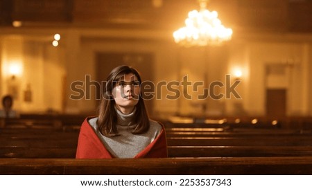 Christian Young Woman Starts Praying Under the Blessed Lights in a Church, Her Thoughts Turning To The Divine Jesus Christ, the Bible and its Teaching. Finds Strength in Sacred Religious Space