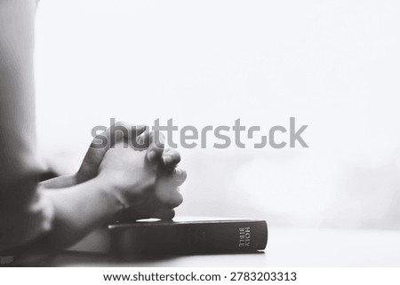 A Christian's devout prayer time, placing both hands on the Bible and offering earnest prayers in silence.
