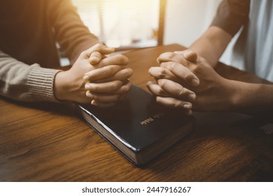 Christians and prayers Group of Christians holding hands praying for faith and Bibles on wooden table for prayer meeting. Sit and pray. - Powered by Shutterstock