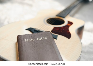 Christians Worship God With A Guitar With The Holy Bible. Reading The Bible And Sharing The Gospel With Copy Space For The Word Of God.