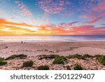 Christies beach with silhouette of a surfer with surfing board and a dog at sunset, South Australia