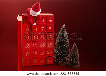 Christmas advent calendar with an elf and gifts on red background