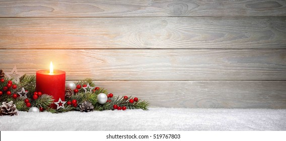 Christmas or Advent wood background with a burning candle on snow, decorated with fir branches and ornaments, panoramic format with copy space - Powered by Shutterstock