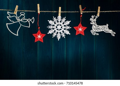 Christmas Angel With Wings And Trumpet, Reindeer, Red Christmas Stars And Snowflakes On Clothespin On Deep Blue Wooden Background With Copy Space. Layout Greeting Card For Winter Holidays. 