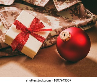 Christmas In The Army. Red Xmas Ball And Gift Box On US America Military Uniform, Closeup View