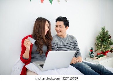 Christmas. Asian Couple Shopping Online At Home Celebrating New Year.