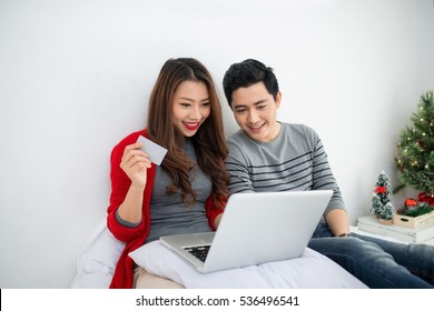 Christmas. Asian Couple Shopping Online At Home Celebrating New Year.