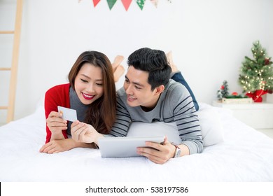 Christmas. Asian Couple Shopping Online At Home Celebrating New Year.