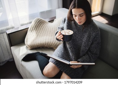 Christmas Atmosphere. Woman Relaxing At Coach, Drinking Hot Chocolate, Reading A Book. Lazy Weekend, Cozy Home, Winter Holidays, Hygge Concept