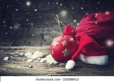 Christmas background with christmas ball, gift, red hat and snow on a wooden background/ Christmas background - Powered by Shutterstock