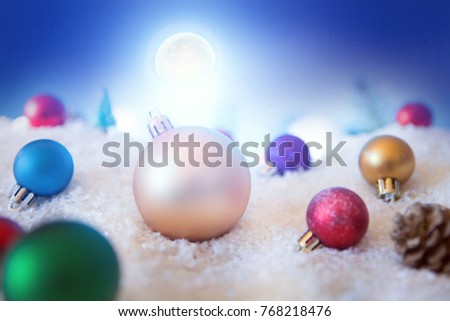 Christmas background with Christmas balls on snow over fir-tree, night sky and moon. Shallow depth of field.
