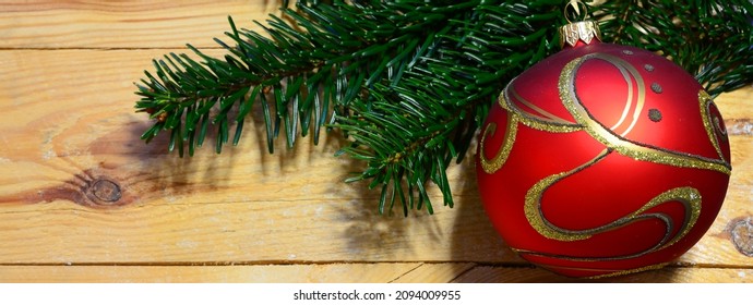 Christmas background banner with fir tree branch and red decorated christmas sphere on wood