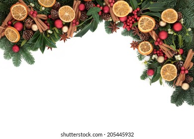 Christmas Background Border With Cinnamon Spice, Dried Orange Fruit, Bauble Decorations, Holly And Winter Greenery Over White With Copy Space.