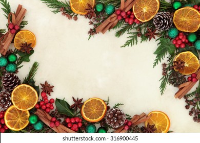 Christmas Background Border With Dried Fruit And Spices, Green Bauble Decorations, Holly And Winter Greenery Over Old Parchment Paper.