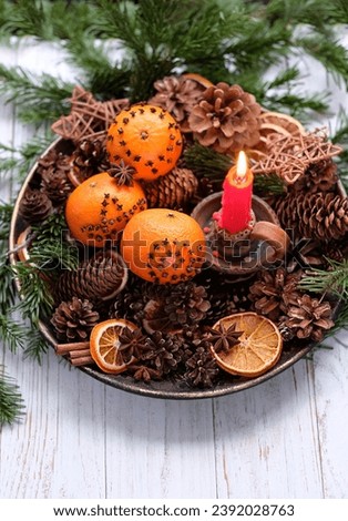 Christmas background. candle, cinnamon, nuts, cones, decorated oranges, fir branches in plate on wooden table. Christmas and new year holidays. Winter altar for Yule sabbath. Festive winter season