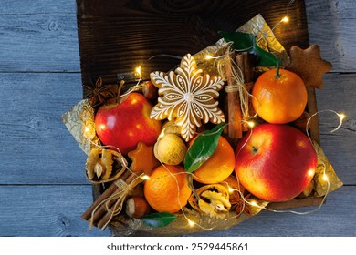 Christmas background card. On the table is a wooden box with gingerbread snowflake, cookies, apples, tangerines, nuts, walnuts, hazelnuts and cinnamon - Powered by Shutterstock