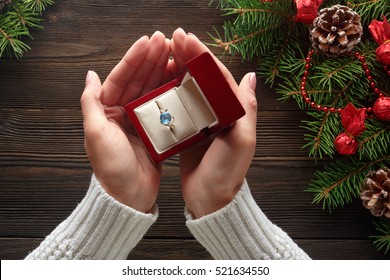 Christmas Background. Engagement Ring In Female Hands Among Christmas Decorations On Wood Background. Romance, Jewelry Concept - Woman Hands With Wedding Ring In Gift Box. Gift On Valentine's Day