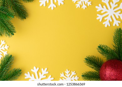 Christmas background with fir branches, snowflake and new year toy red ball or bauble flat lay on yellow pastel  background. Top view. Minimal concept. - Powered by Shutterstock