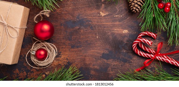 Christmas background with fir tree branch, gifts, candy canes and present box on wooden background. Flat lay, top view, copy space - Image