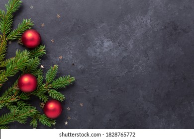 Christmas background with fir tree and red balls on dark stone background. Top view Copy space - Image