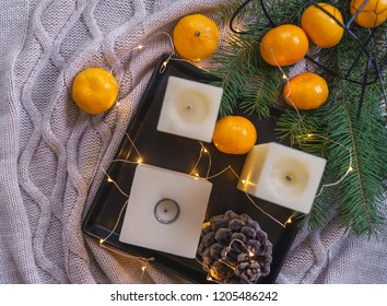 Christmas background. Flat lay to candles, orange tangerines, pine cone fir on black tray fairy lights on gray plaid background. Christmas decorations inspiration, layout idea. Top view copy space - Shutterstock ID 1205486242